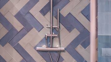 A shower with a handheld showerhead and a wall-mounted control panel.