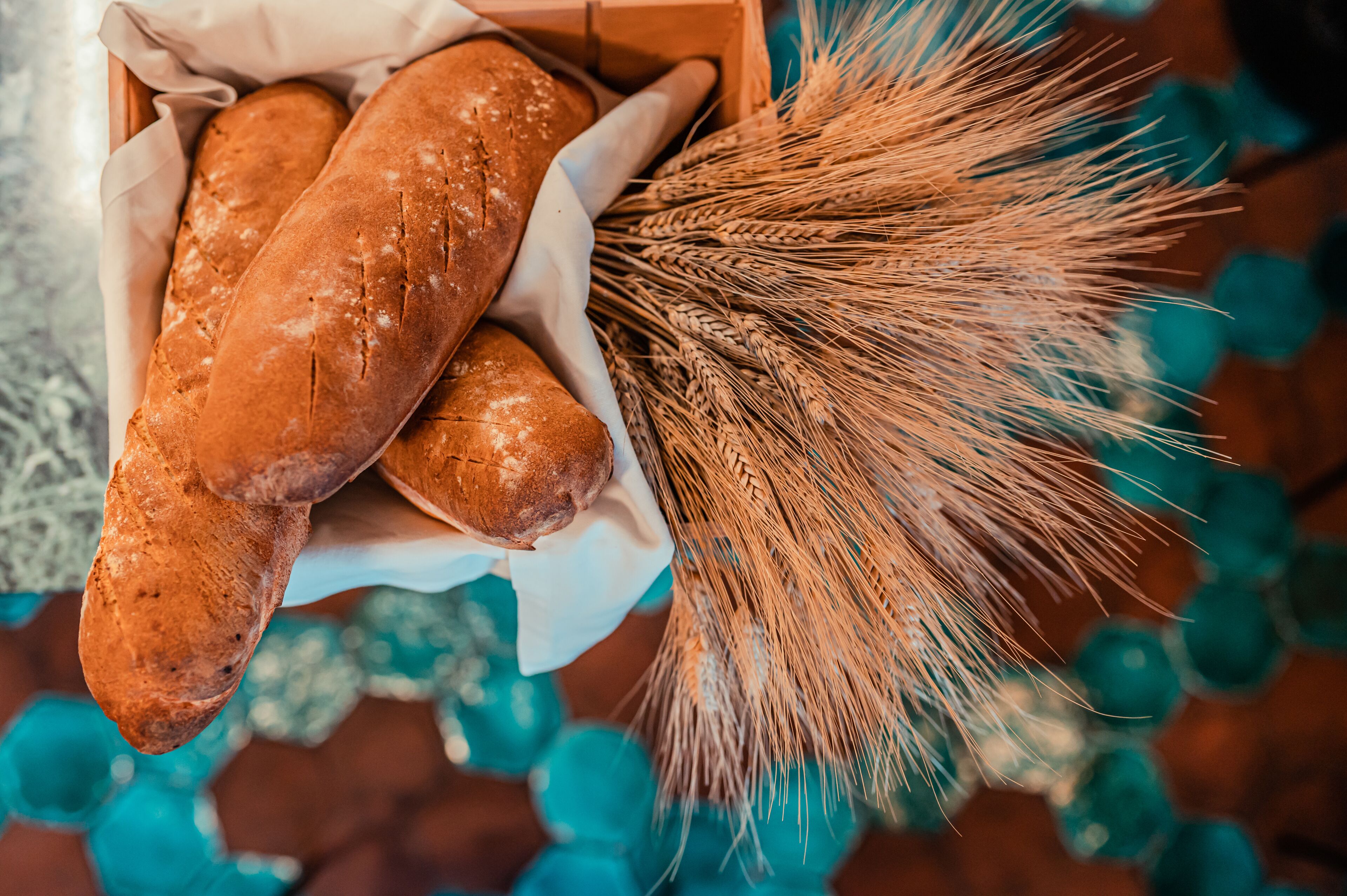A box containing several loaves of bread and a bundle of wheat stalks.