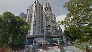 A multi-story residential building with balconies, a covered entrance, and a small adjacent structure.