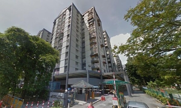 Un edificio residencial de varios pisos, con balcones, un acceso cubierto y una pequeña construcción adyacente.