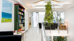 Amplia sala de estar con techo alto, una gran estantería, un cuadro y una planta colgante.