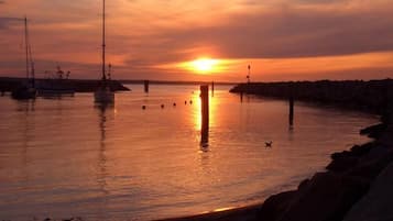 A sunset over a calm harbor with boats and a pier.
