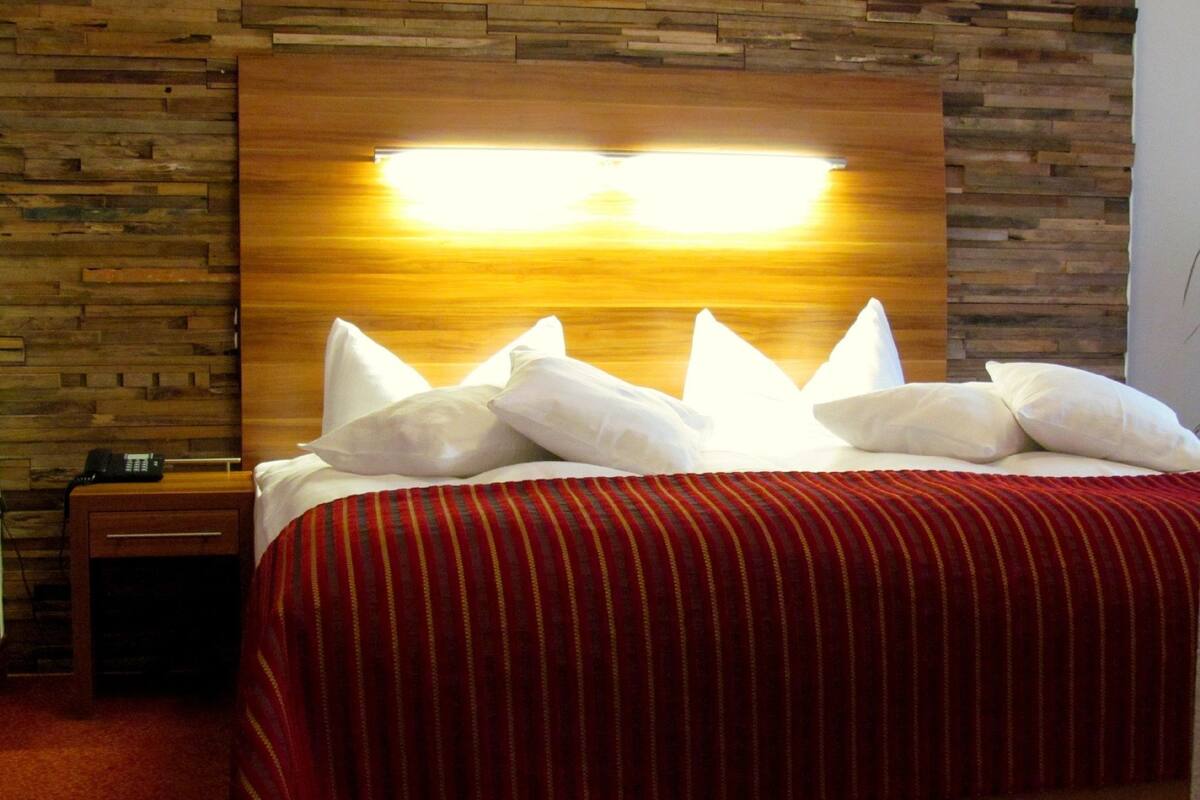 Ein Hotelzimmer mit einem hölzernen Kopfteil, einer rot-weiß gestreiften Bettdecke und weißen Kissen.