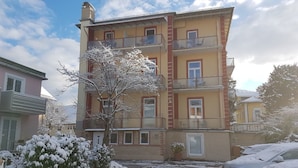 A multi-story residential building with balconies, a snow-covered ground, and a parked car. - Hotel Almrausch (Bad Reichenhall)