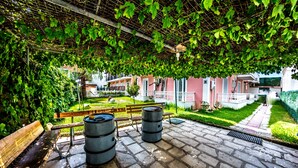 A covered patio with stone flooring, a wooden bench, and metal barrels. - Terra Azzura (Zakynthos)