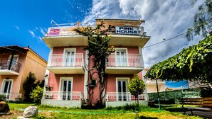 A multi-story building with a balcony and a sign that reads "PINK HOUSE." - Terra Azzura (Zakynthos)