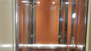 An elevator interior with metallic walls and a central brown panel. - Terra Azzura (Zakynthos)