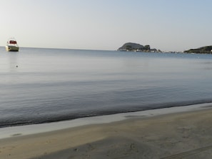 A calm beach with a boat in the water and a distant island. - Terra Azzura (Zakynthos)