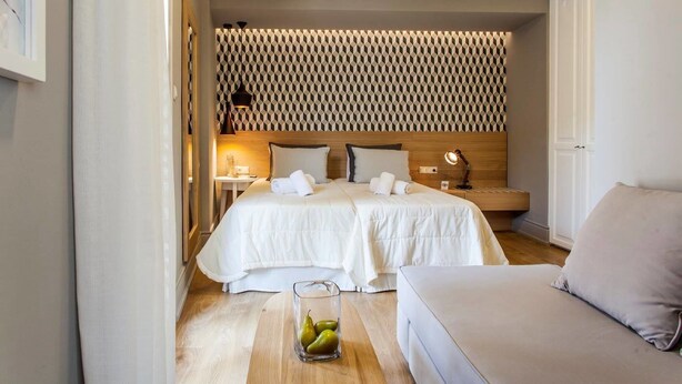 A hotel room with a bed, bedside tables, a lamp, and a seating area.
