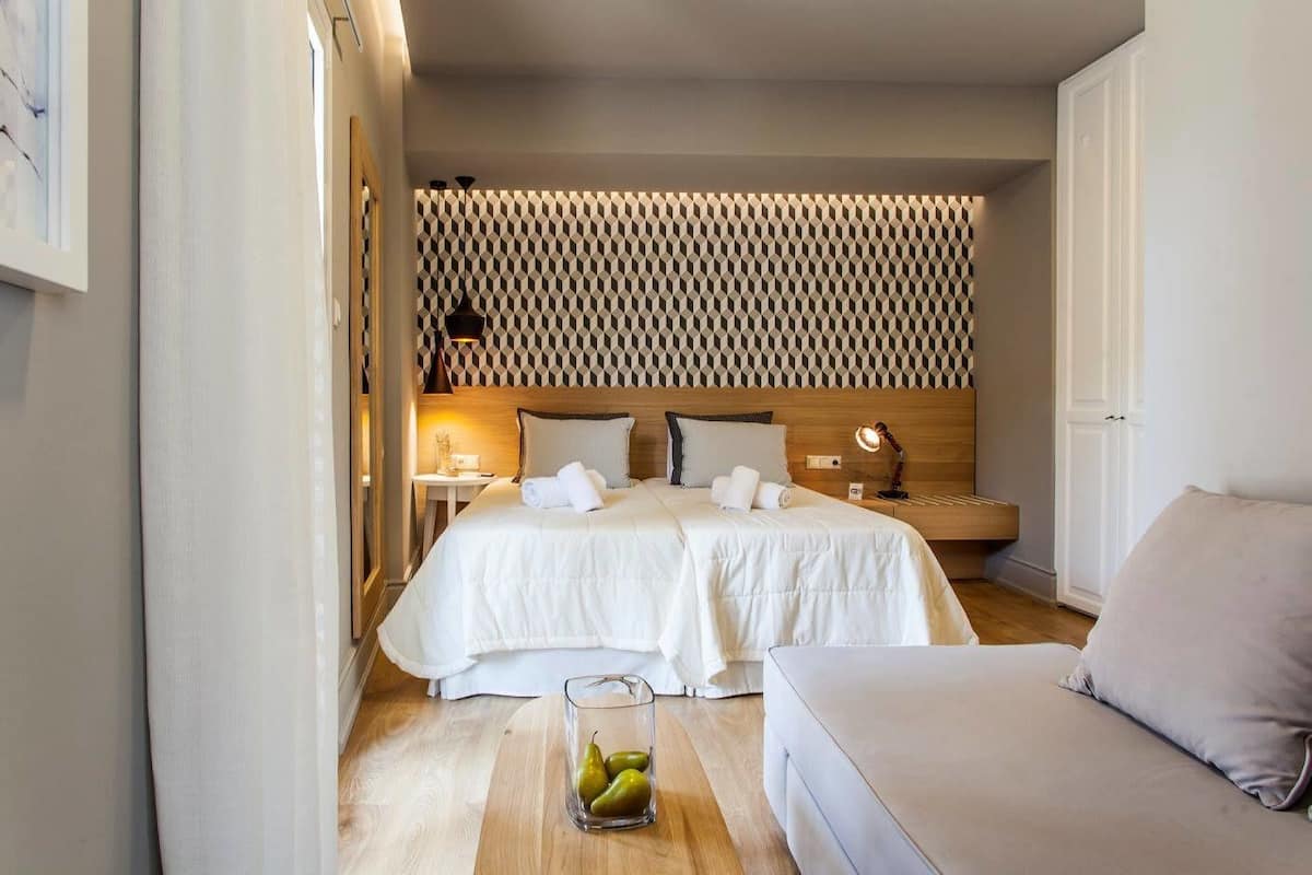 Een hotelkamer met een bed, nachtkastjes, een lamp en een zithoek.