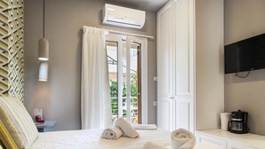 A hotel room with a bed, a TV, an air conditioner, and a window with curtains.