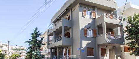 A multi-story residential building with balconies and a parking area.
