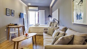 A modern living room with a sofa, a small table, and a TV on the wall.