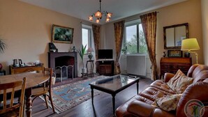 A living room with a fireplace, leather sofa, wooden coffee table, and a television. - Les Voisins de l'Illet (Ercé-près-Liffré)