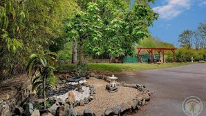 A garden with a stone pathway, a gazebo, and a pond with a statue. - Les Voisins de l'Illet (Ercé-près-Liffré)