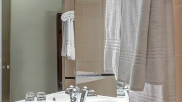 Un baño moderno con un lavamanos blanco, dos frascos de vidrio y una toalla colgada en un perchero.
