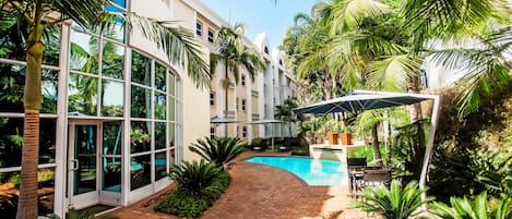 Una piscina al aire libre, sombrillas, sillones reclinables de piscina