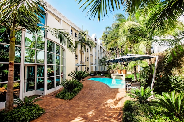 Una piscina al aire libre, sombrillas, tumbonas