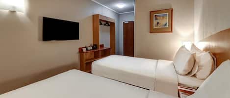 Een hotelkamer met twee bedden, een televisie, een houten garderobe en een lijst met een afbeelding aan de muur.