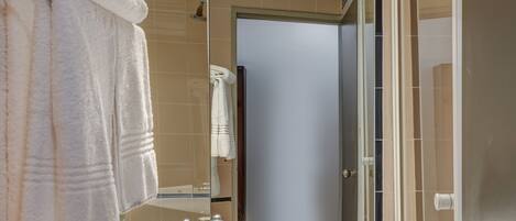A modern bathroom with a large mirror, two sinks, and a glass shower enclosure.