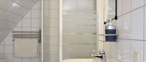 Un bagno moderno con un lavandino bianco, cabina doccia in vetro e porta asciugamani.