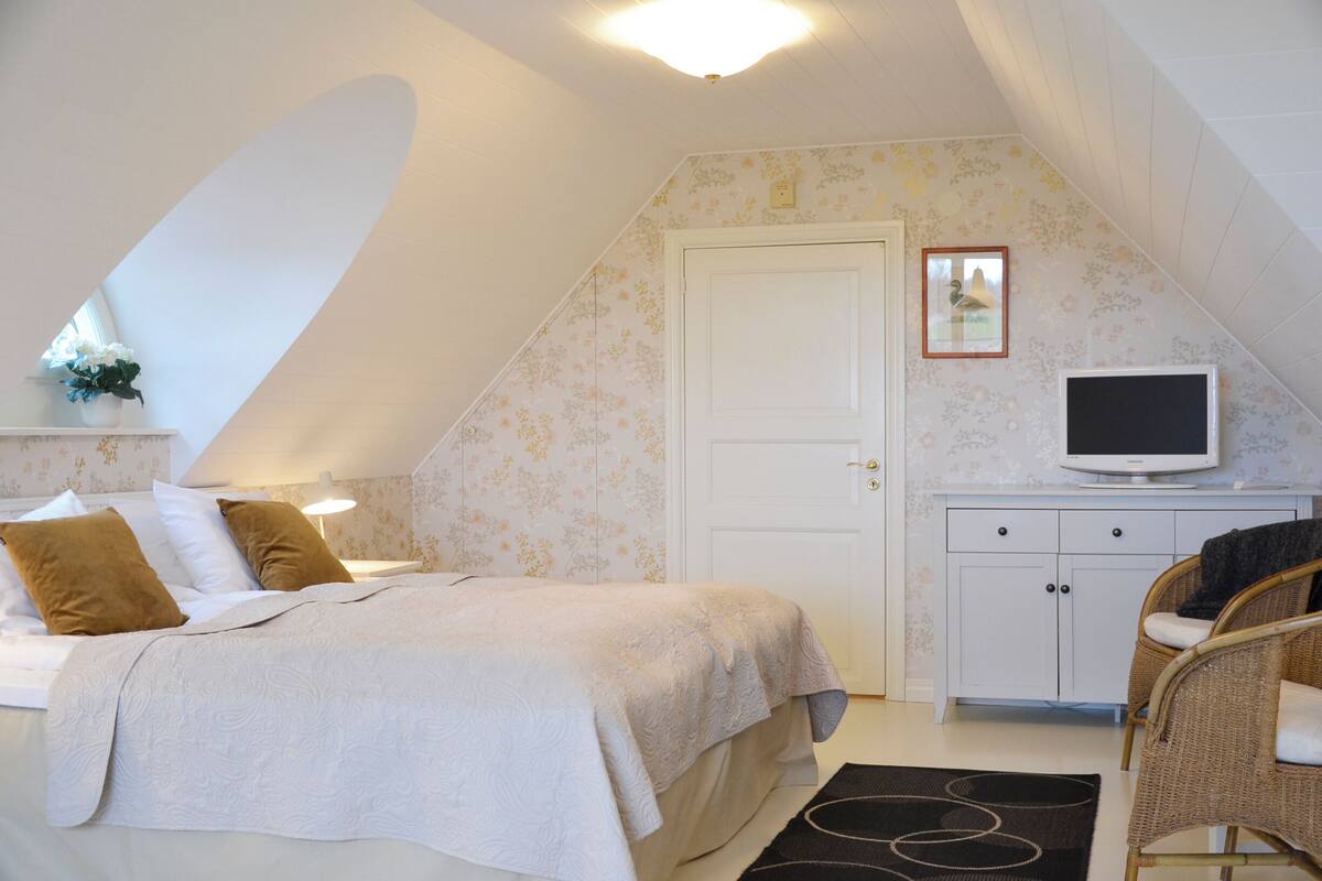 A bedroom with a bed, a television on a cabinet, and a chair.