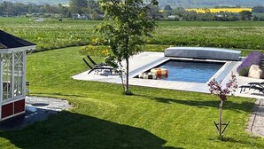 En swimmingpool med en patio, et overdækket siddeområde og udsigt over landskabet.