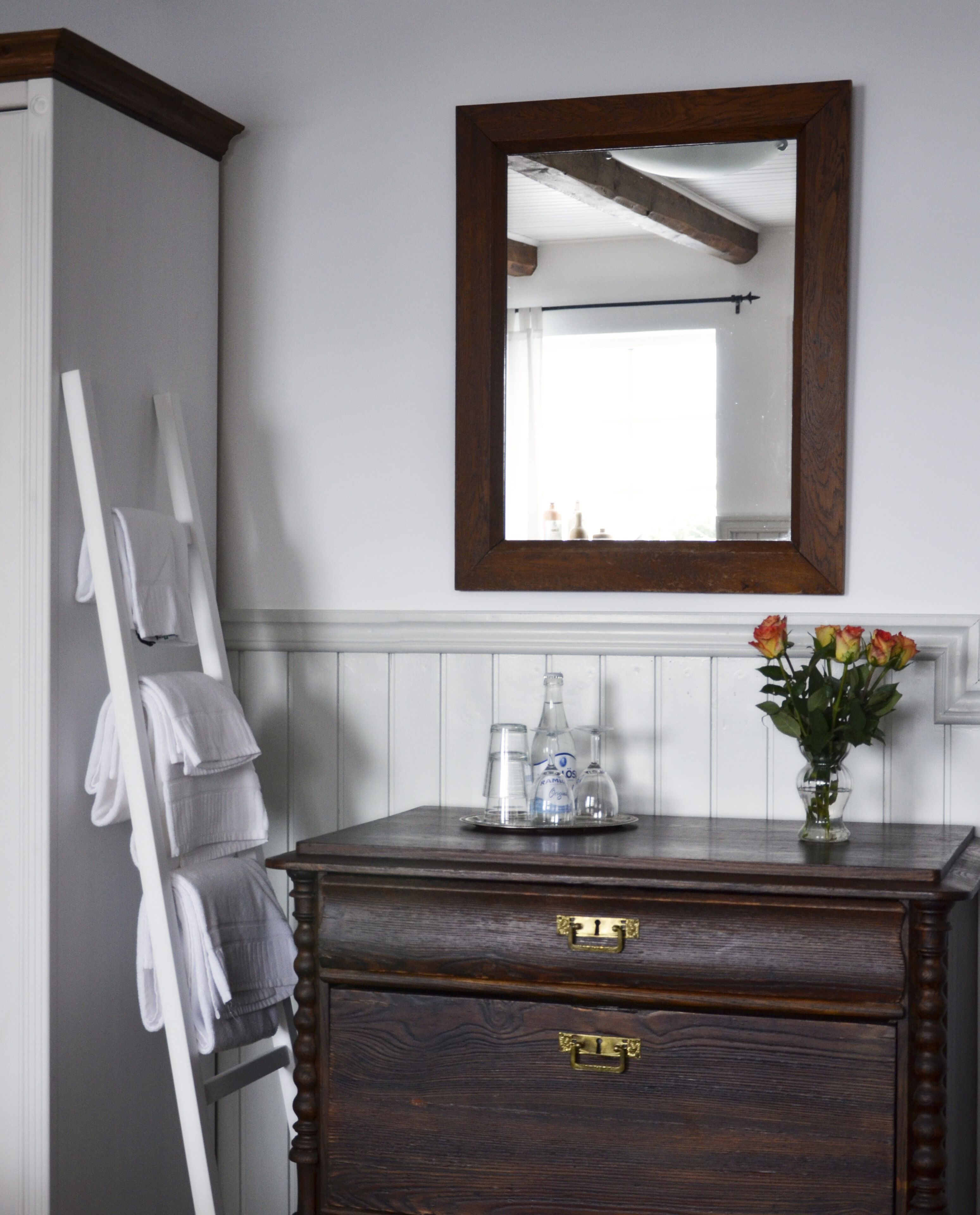 A bathroom with a wooden vanity, a mirror, and a towel rack.