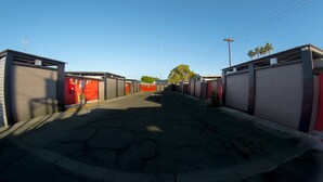 A street with buildings on both sides, featuring garage doors and a clear sky. - Motel Las Dunas (Mexicali)