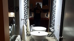A narrow bathroom with a large mirror, a white sink, and a tiled backsplash. - Motel Las Dunas (Mexicali)