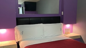 A hotel room with a bed, a large mirror, and two bedside tables with lamps. - Motel Las Dunas (Mexicali)