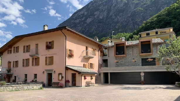 A traditional Italian building with a stone facade, a balcony with flowers, and a paved courtyard. - Italo-Svizzero (San Giacomo Filippo)