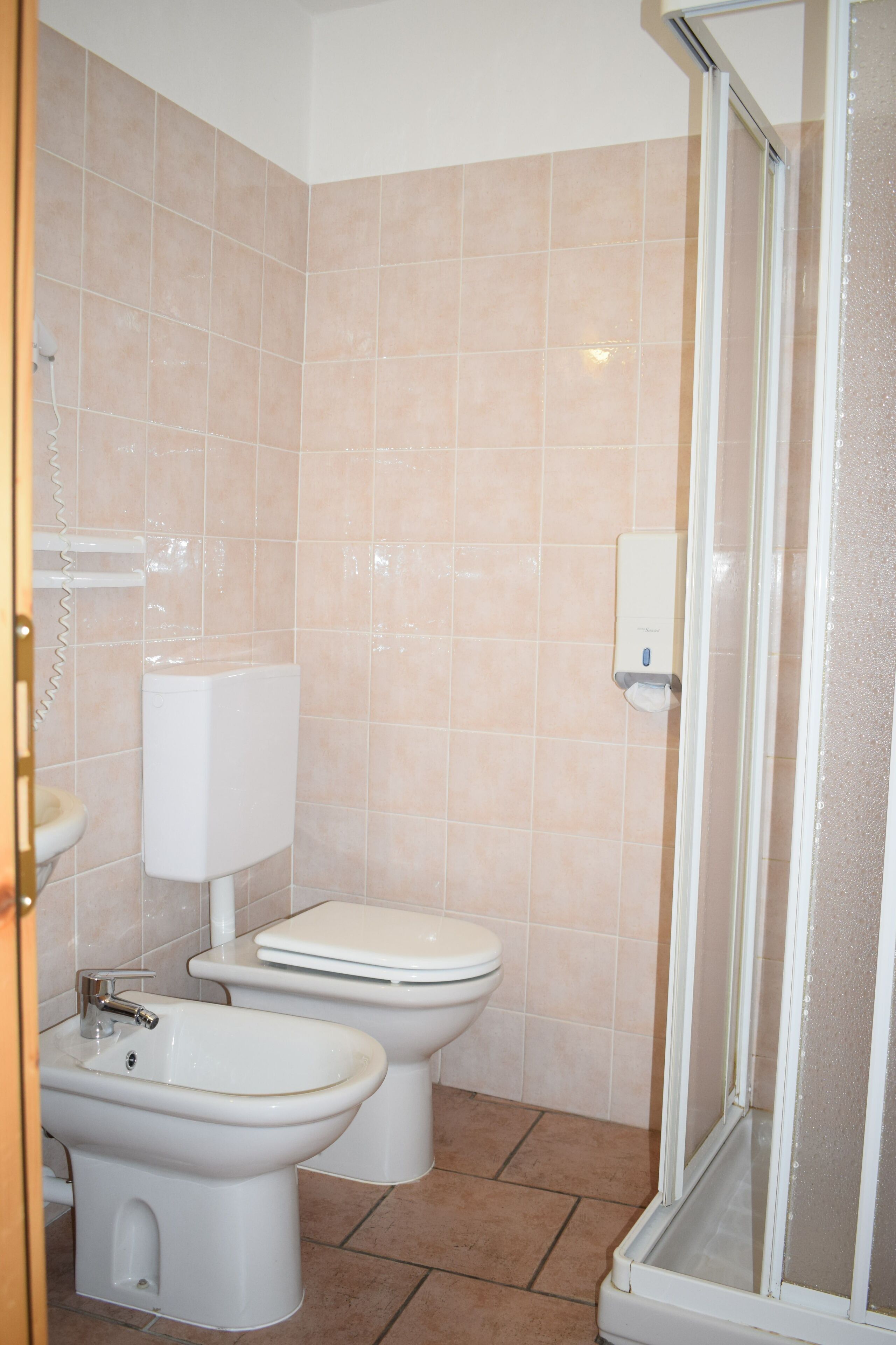 Un baño con inodoro, bidé y ducha con mampara de vidrio.