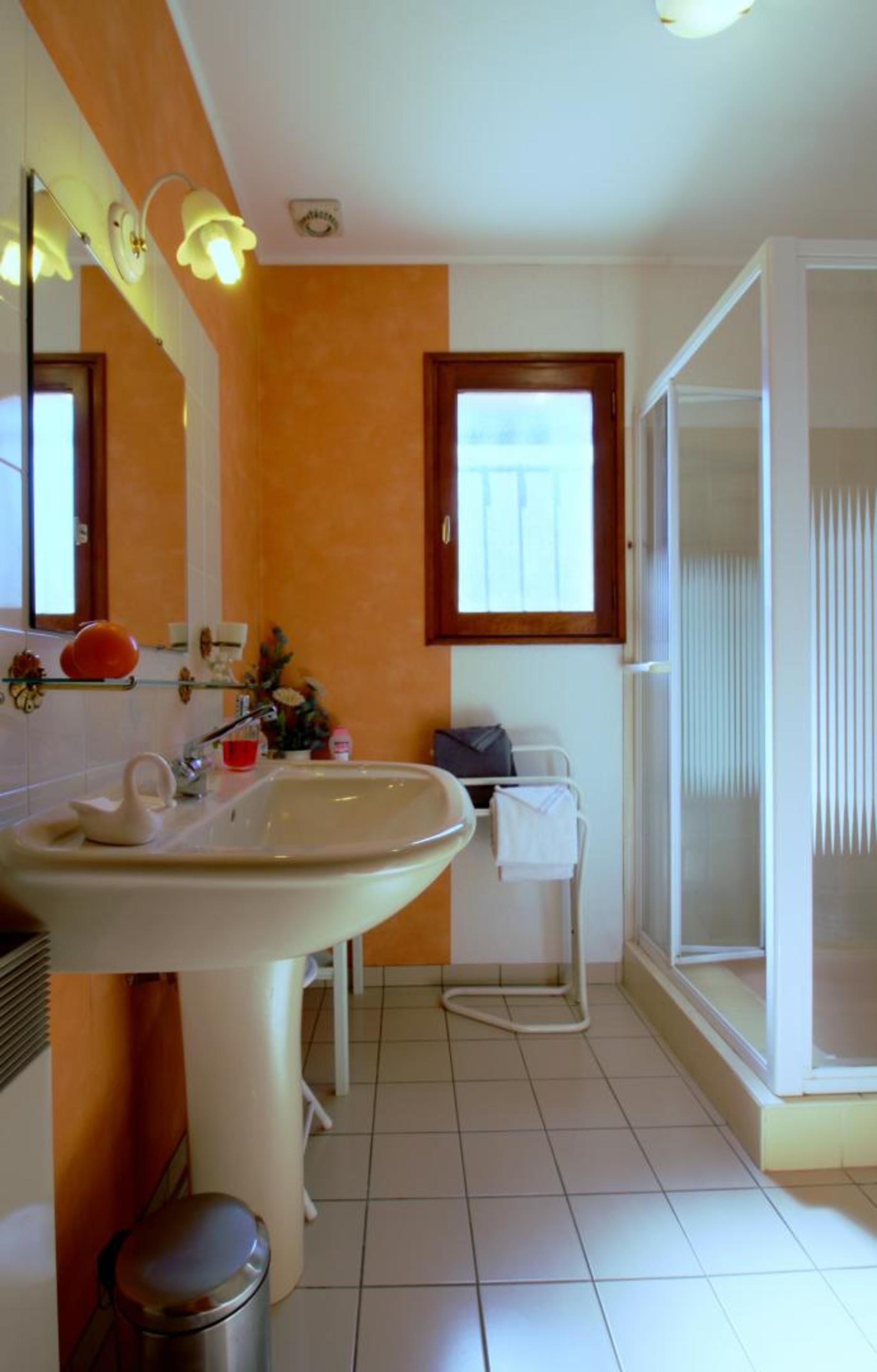 Une salle de bain avec un lavabo, un miroir et une fenêtre.