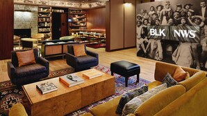 A modern library with bookshelves, a coffee table, sofas, and a large wall mural.