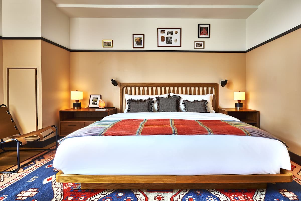 A neatly made bed with a patterned bedspread, wooden headboard, and two bedside lamps.