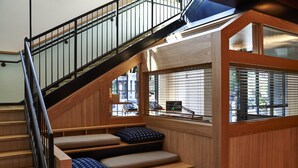A staircase with wooden steps and black railings, leading to a landing with a view of the outside.