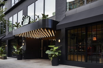 A modern interior with tiered hanging lamps, seating areas, and abundant indoor plants. at Eaton DC