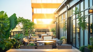 An outdoor patio with seating, potted plants, and a building with large windows in the background. - Eaton DC (Washington)