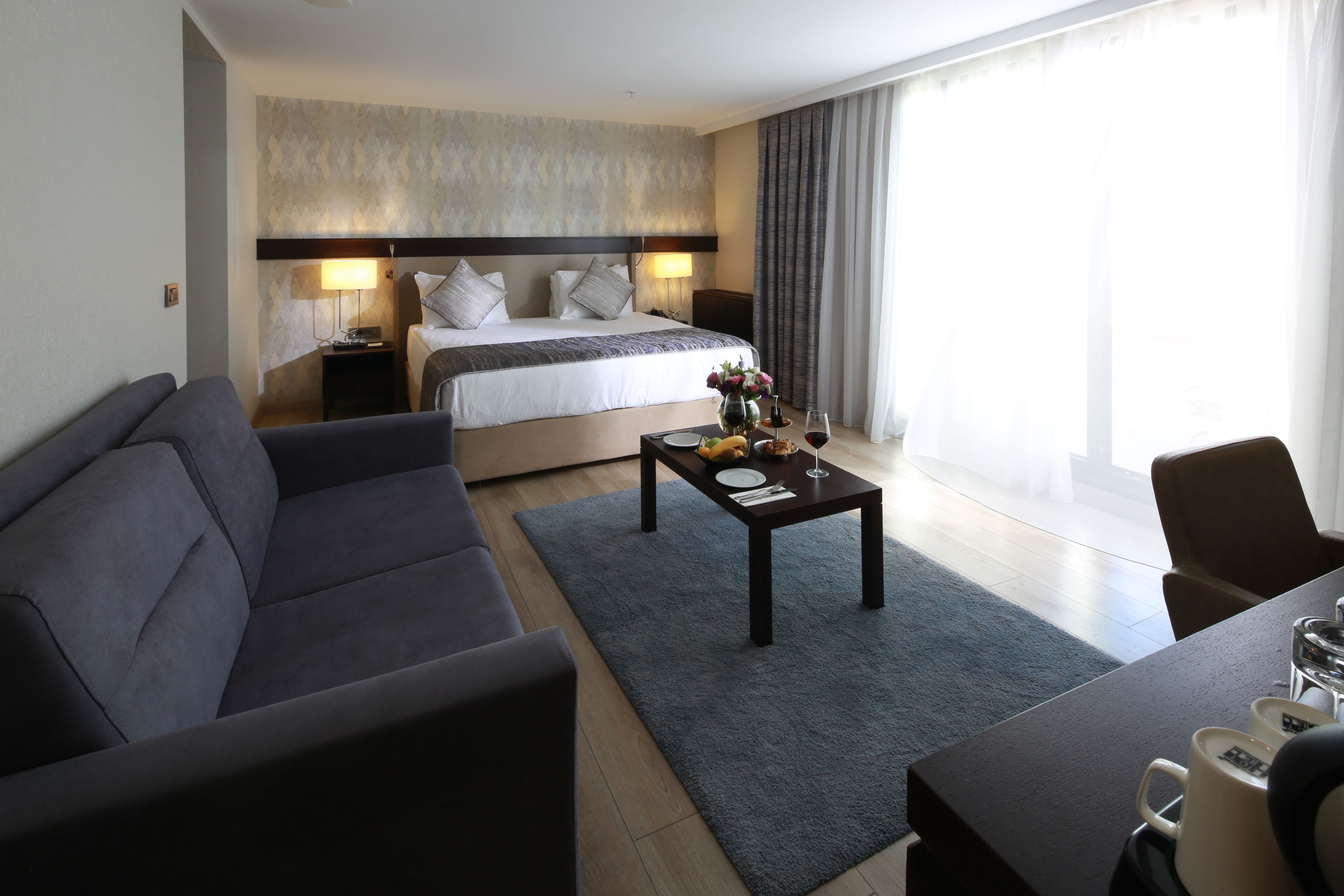 Ein modernes Hotelzimmer mit einem großen Bett, einer Couch, einem Couchtisch und einem Essbereich.