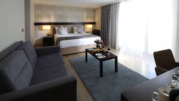 Ein modernes Hotelzimmer mit einem großen Bett, einer Couch, einem Couchtisch und einem Essbereich.