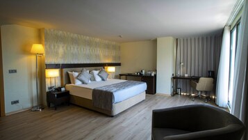 Habitación de hotel con una cama grande, mesitas de noche, un escritorio, una silla y una lámpara.