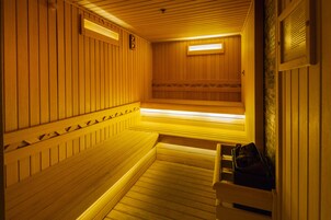 Una sauna con bancos de madera, un banco con una toalla y un calentador fijado a la pared.