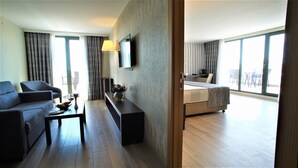 Habitación de hotel con sofá, mesa de centro, televisión y cama.