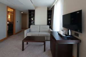 Una sala de estar moderna con un sofá, una mesa de centro, un televisor y una estantería.