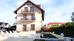 A multi-story building with balconies, a swimming pool, and lounge chairs. - Dolce  Vita (Ustronie Morskie)