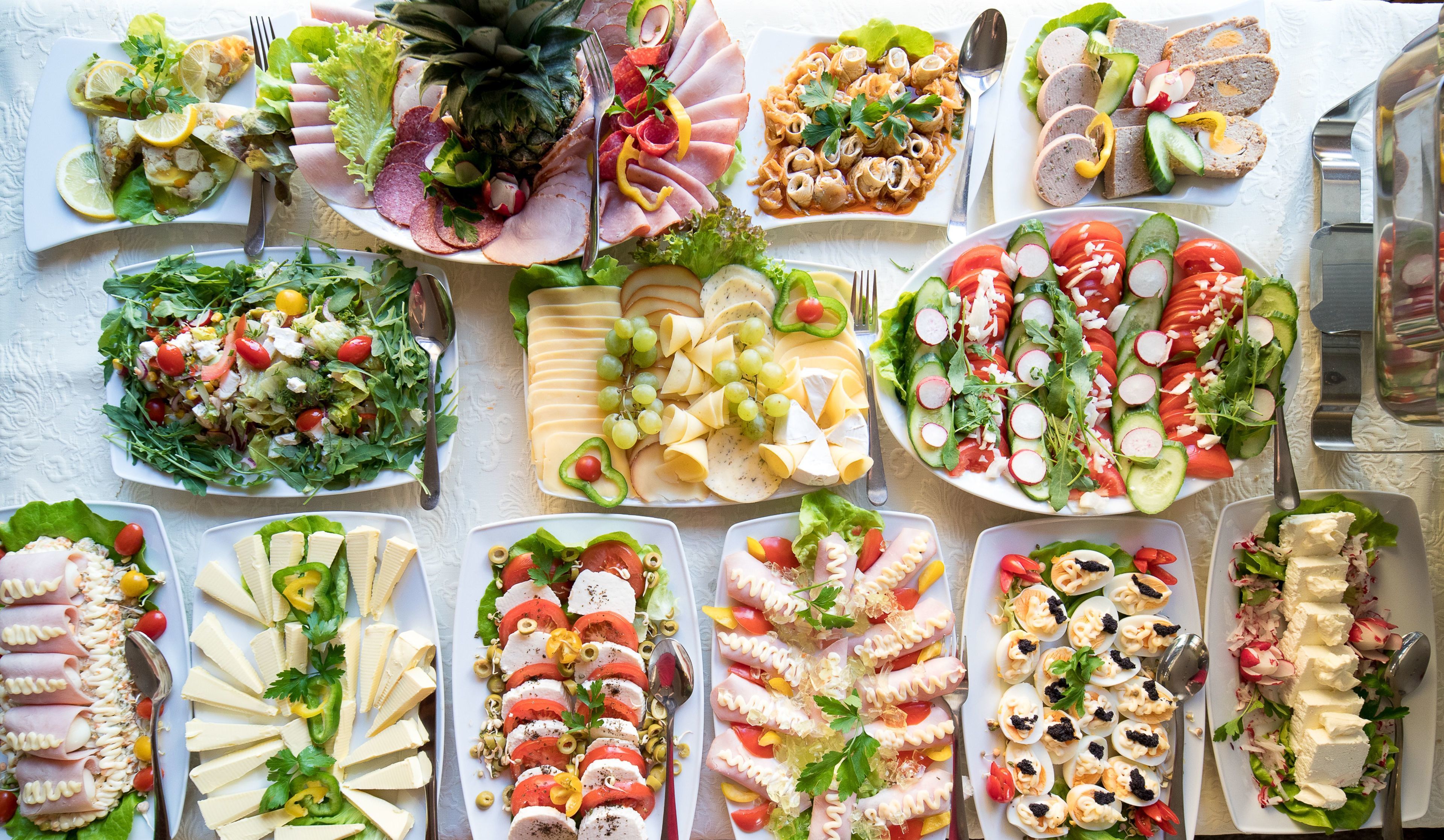 A variety of food platters including salads, cheeses, and meats, arranged on a table.