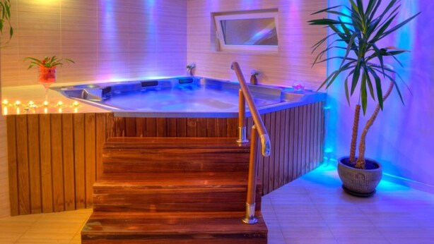 A wooden staircase leading to a hot tub area with a wooden railing and a potted plant. - Dolce  Vita (Ustronie Morskie)