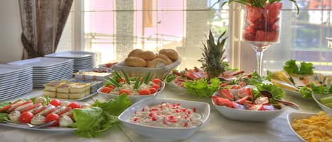 A buffet table with various food items and a potted plant.