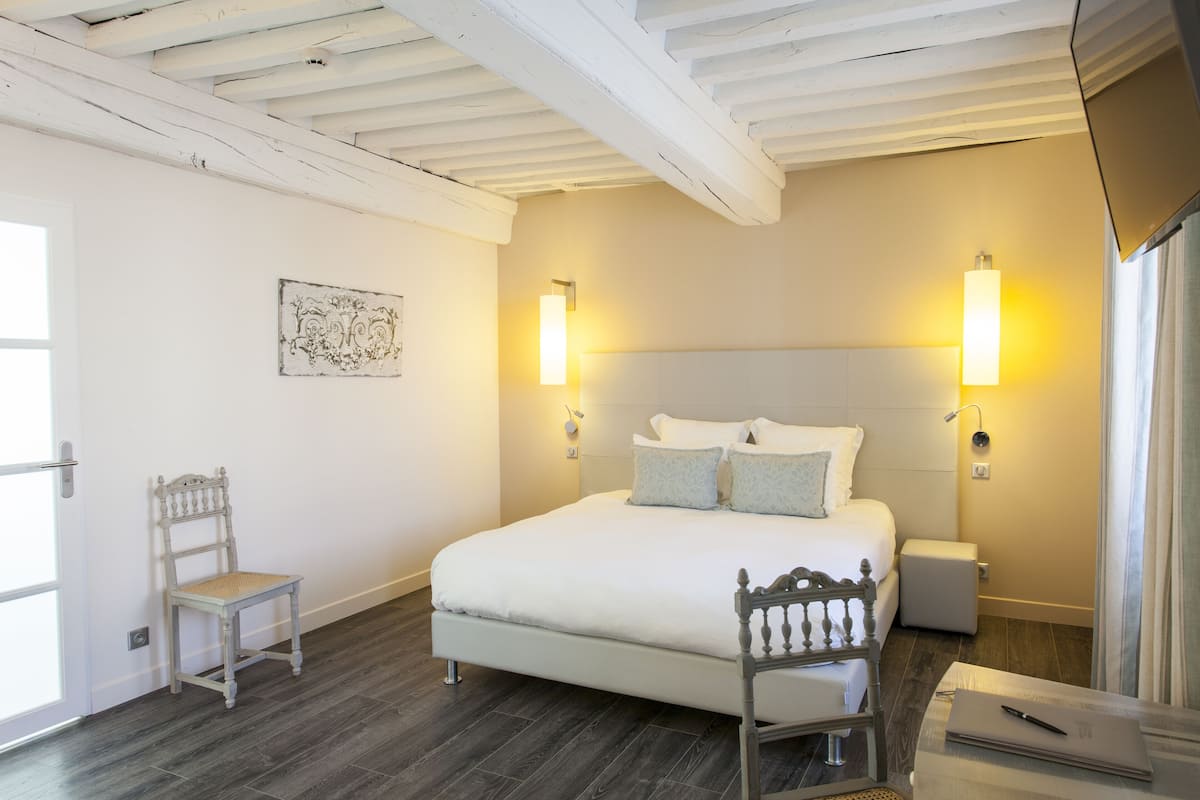 A bedroom with a large bed, two bedside lamps, a chair, a bedside table, and a small bedside table.